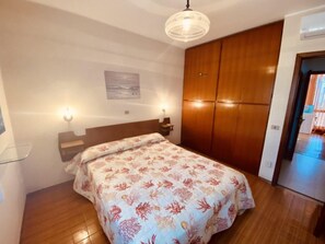 Ein Schlafzimmer mit einem Bett, einem Holzschrank, einer Wandleuchte und einem Bild.