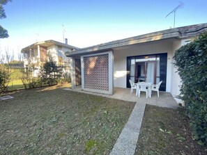 Ein Wohnhaus mit überdachter Terrasse, kleinem Rasen und zweiflügeliger Eingangstür.
