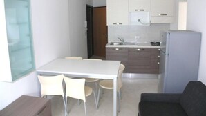 Una cocina compacta con una mesa de comedor, sillas, un refrigerador y armarios.