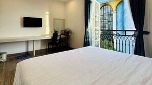 Hotelkamer met een bed, bureau, stoel, televisie en een balkon met uitzicht.