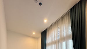 Een kamer met een bank, een ventilator en een raam met gordijnen.