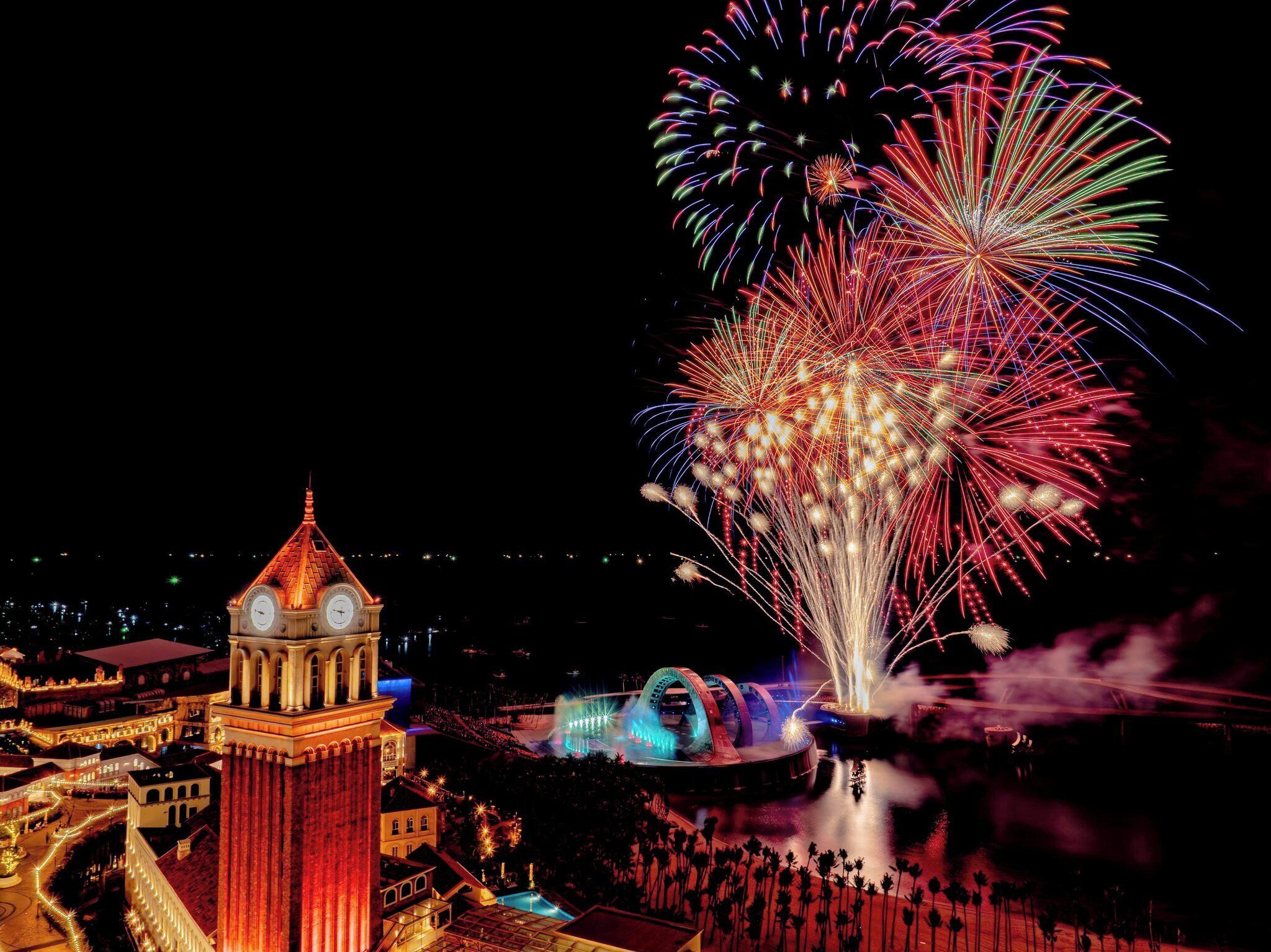 A historic clock tower and a fireworks display over a cityscape.
