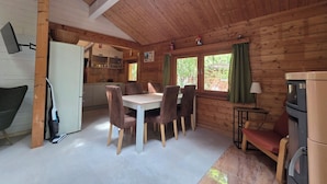 A wooden cabin interior with a dining table, chairs, a kitchen area, and a fireplace. - Idyllic wooden house on the Steinhuder Meer (Neustadt am Rübenberge)