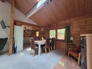 L’intérieur d’un chalet en bois comprend une table à manger, des chaises, un coin cuisine et une cheminée.