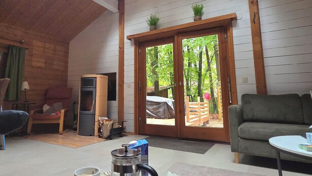 A cozy room with a skylight, a dining table with breakfast items, a sofa, and a sliding glass door leading to an outdoor area. - Idyllic wooden house on the Steinhuder Meer (Neustadt am Rübenberge)