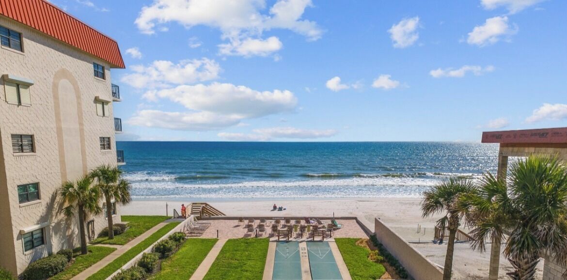 Un hôtel situé en bord de mer, doté d’une piscine, de palmiers et offrant une vue sur l’océan.