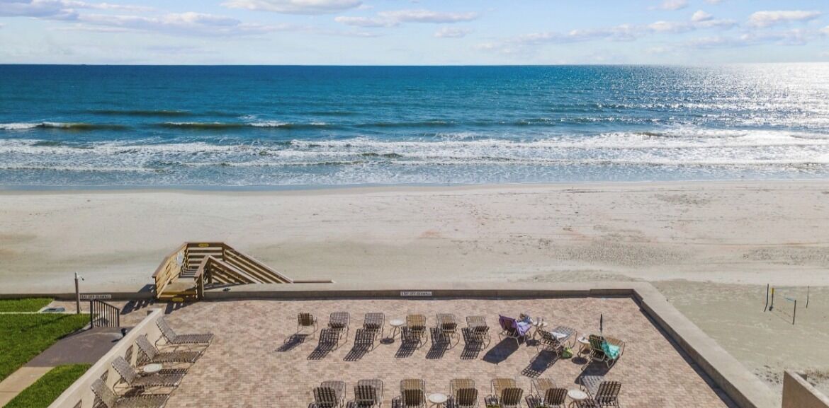 A beachside view with a row of sun loungers and a staircase leading to a higher level.
