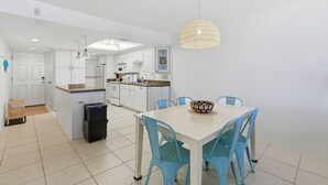 Uma cozinha moderna com armários brancos, uma mesa de jantar com cadeiras azuis e um lustre.