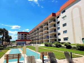 Um hotel com várias varandas, piscina e um jardim bem cuidado.