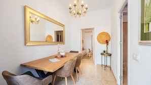 Un comedor con una mesa de madera, sillas, una araña y un espejo grande en la pared.