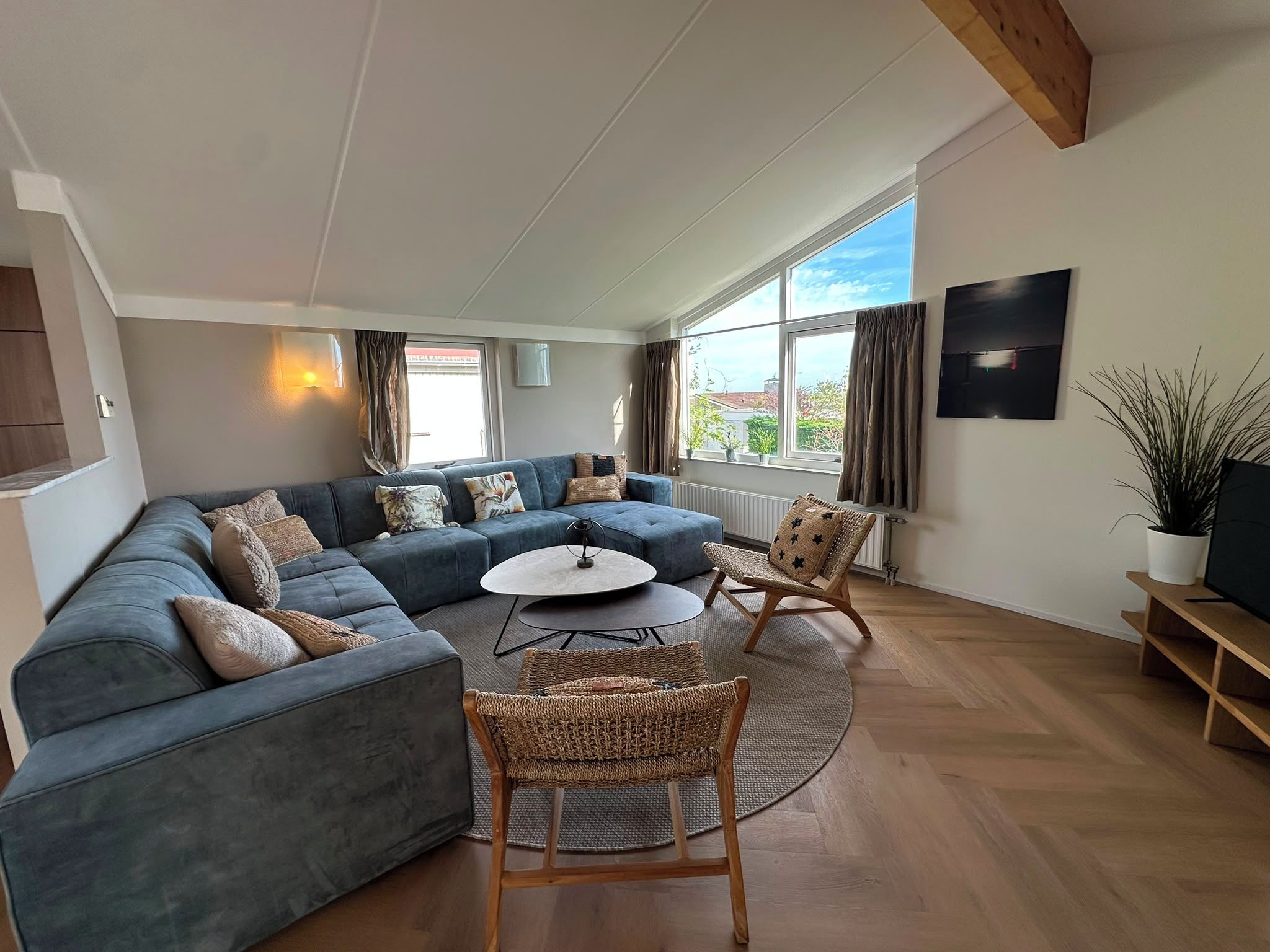 A modern living room with a sectional sofa, a round coffee table, and wicker chairs.