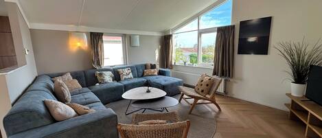 A modern living room with a sectional sofa, a round coffee table, and wicker chairs.
