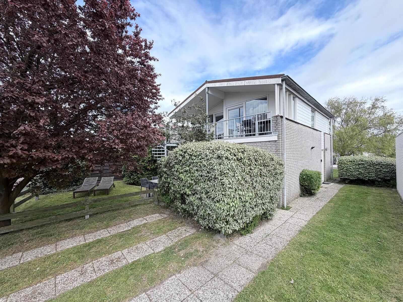 Une maison à deux étages dotée d’un balcon, d’une allée pavée et d’une pelouse bien entretenue.