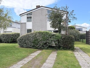A modern two-story house with a brick facade, a well-maintained lawn, and a gravel pathway.