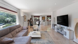 Una sala de estar moderna con sofá, televisor y comedor.