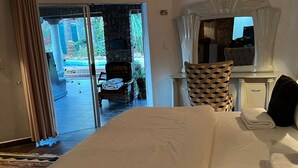 Een hotelkamer met een bed, een stoel, een bureau en uitzicht op een buitenzwembad.