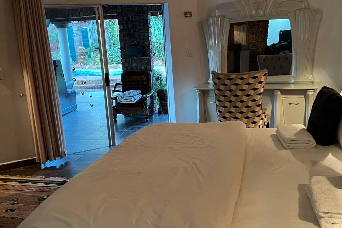 Habitación de hotel con cama, una silla, un escritorio y vistas a un área de piscina exterior.