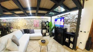 A living room with a sofa, a coffee table, a TV, and a stone wall.