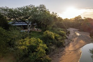 Ein Haus mit überdachter Terrasse, umgeben von üppigem Grün und einem Fluss.