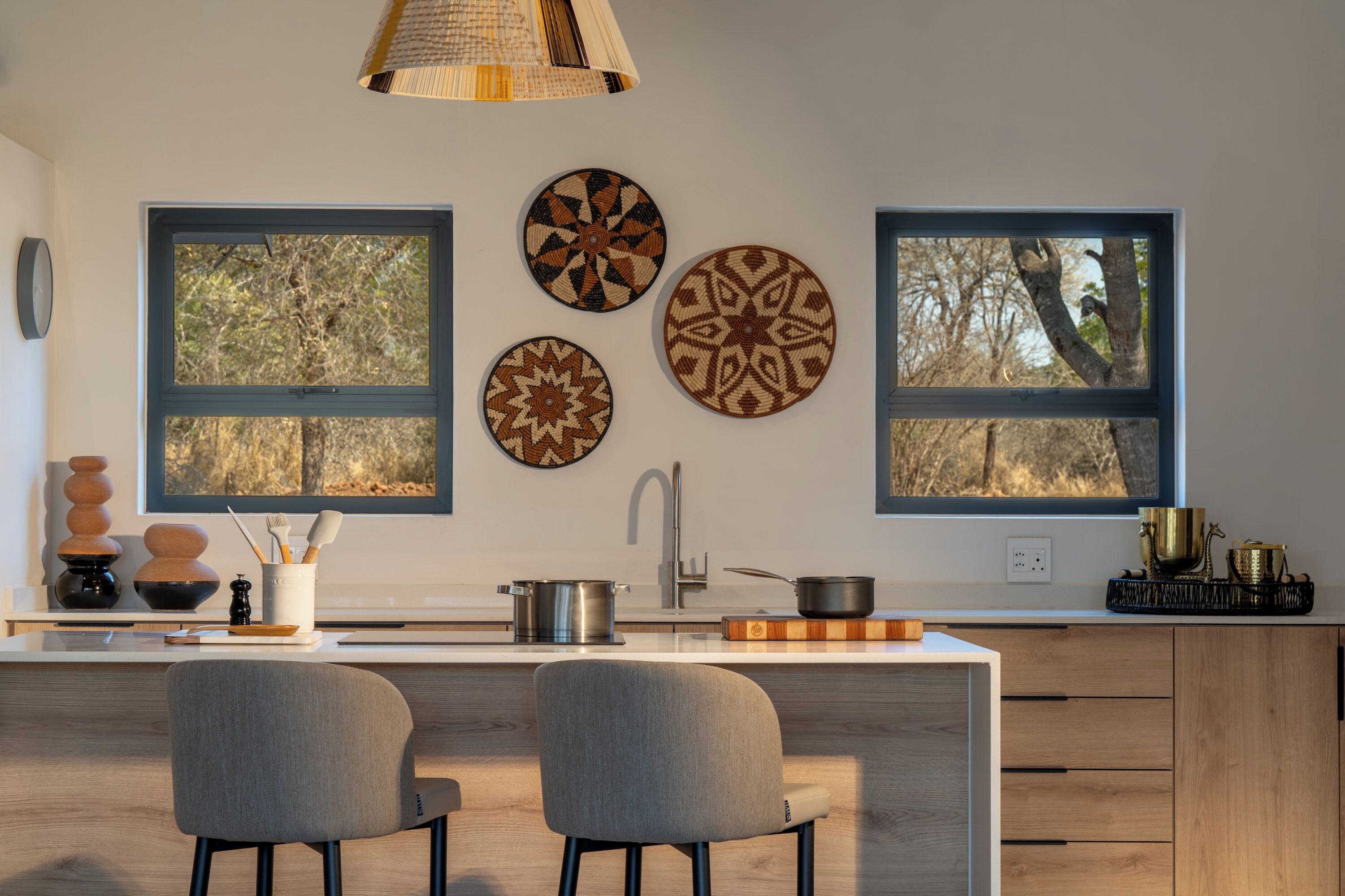 Une cuisine moderne avec un îlot central, deux chaises, un évier et des assiettes décoratives accrochées au mur.