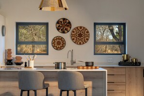 Eine moderne Küche mit einer zentralen Kochinsel, zwei Stühlen, einer Spüle und dekorativen Tellern an der Wand.