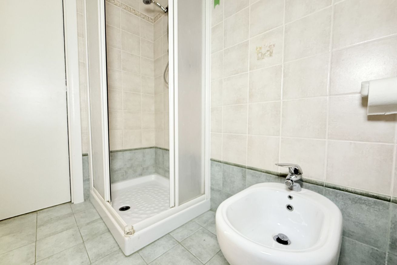 A bathroom with a shower, a sink, and tiled walls.