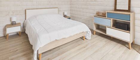 A bedroom with a wooden bed, a nightstand, a dresser with drawers, and a mirror.