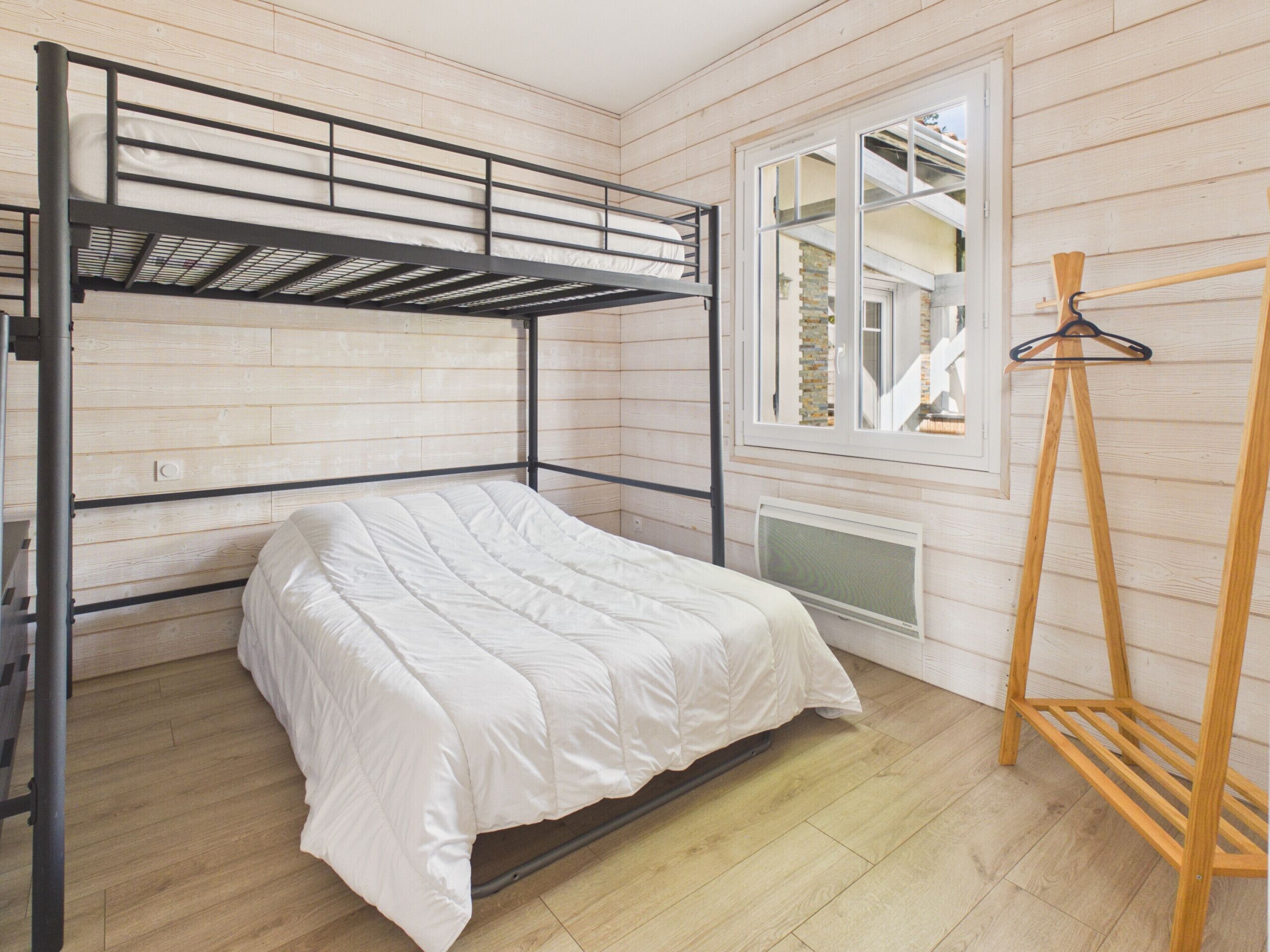 Dormitorio con literas, ventana y escalera de madera.