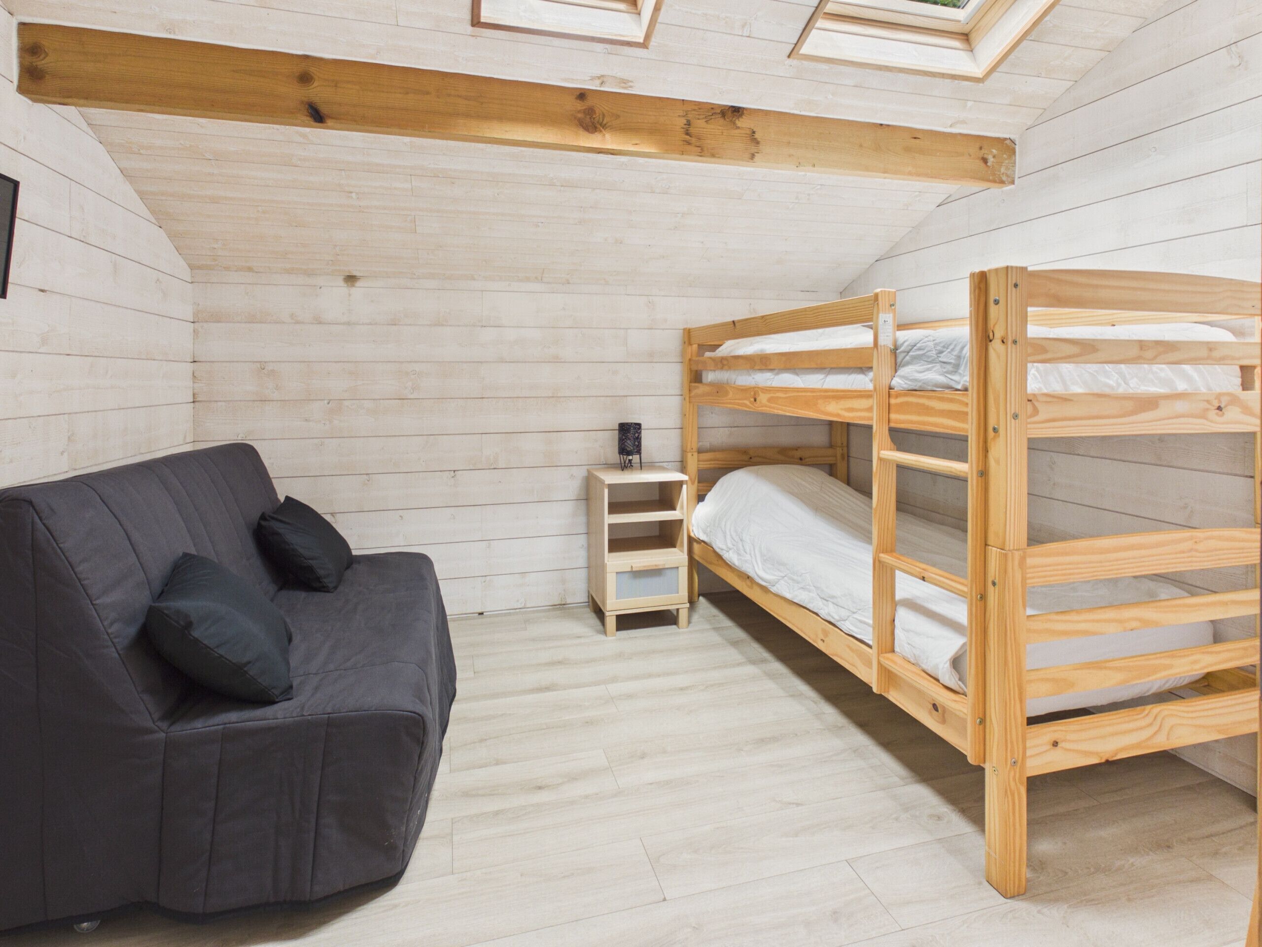 A room with a bunk bed, a sofa, and a small table.