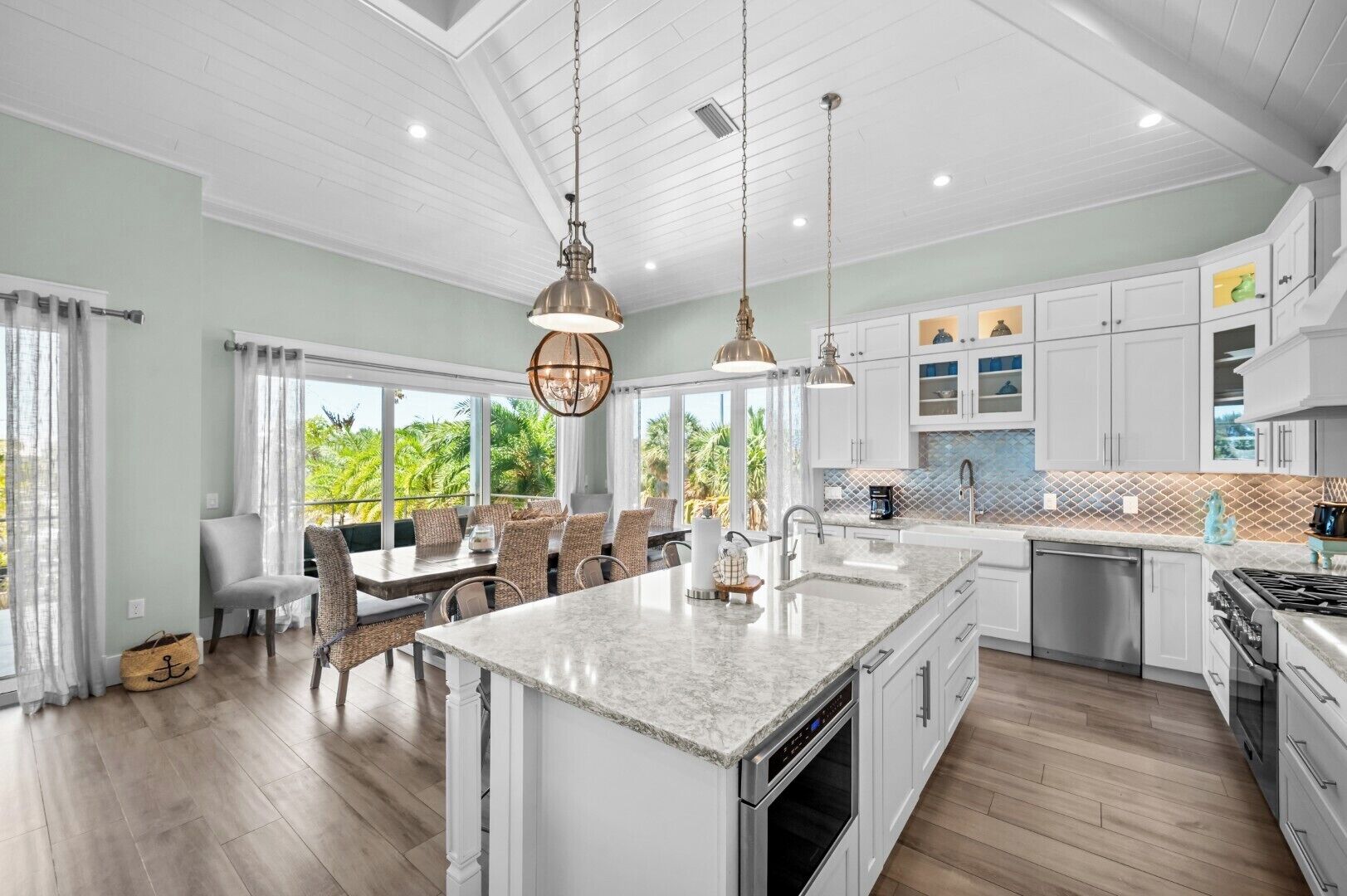 A spacious kitchen with a large island, white cabinetry, and a view of the outdoors.