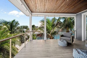 A covered outdoor area with a wooden ceiling, a pool, and a view of palm trees. - Casa Azul by Beach Boutique Rentals (Anna Maria)