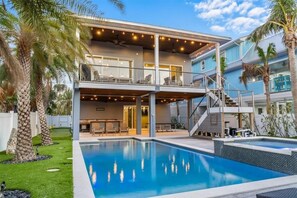 A two-story house with a pool, outdoor seating, and palm trees. - Casa Azul by Beach Boutique Rentals (Anna Maria)