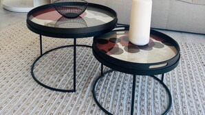 A living room with a grey sofa, two round tables with black frames, a white vase, and a woven rug. - A stunning 4-bedroom home with swimming pool in Puerto Addaia, Menorca. (Port d'Addaia)