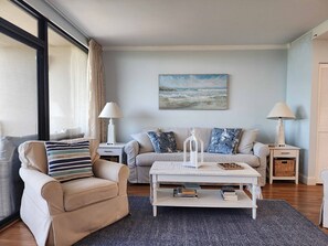 Ein Wohnzimmer mit einer Couch, Sesseln, einem Couchtisch und Lampen.