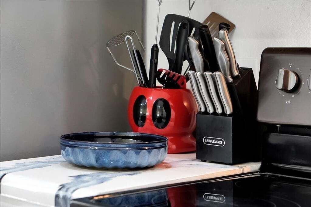 Una encimera de cocina con un tazón azul, un portalápices rojo y un electrodoméstico negro.