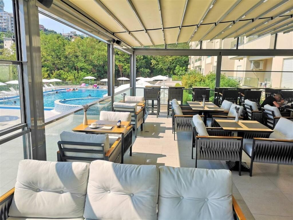 Una terraza en la azotea con piscina, zonas de estar y vistas a la vegetación circundante.