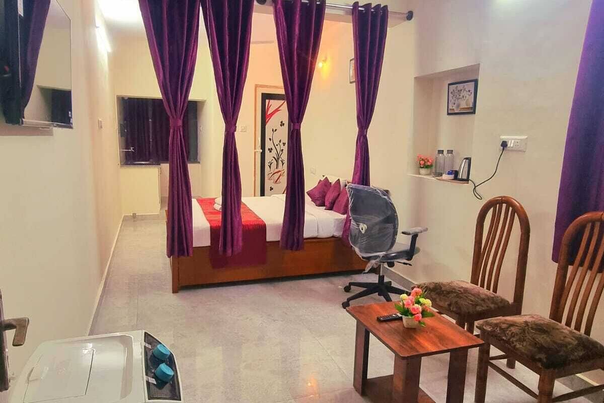 Habitación de hotel con cama, escritorio, silla, ventilador de techo y zona de ducha.