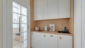 A modern kitchen with white cabinets, a wooden countertop, and a coffee maker. - Sea & Monte City Center Apartments Sopot (Sopot)