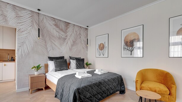 A modern bedroom with a bed, a nightstand, a chair, and artwork on the wall. - Sea & Monte City Center Apartments Sopot (Sopot)