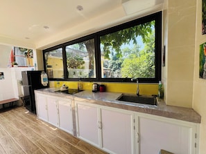 Una cocina con un ventanal grande, un fregadero, armarios y un refrigerador.