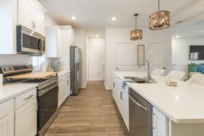 Una cocina moderna con armarios blancos, electrodomésticos de acero inoxidable y una isla central con fregadero.