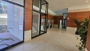 Eine großzügige Lobby mit Glaswand, Treppe und einer Topfpflanze.