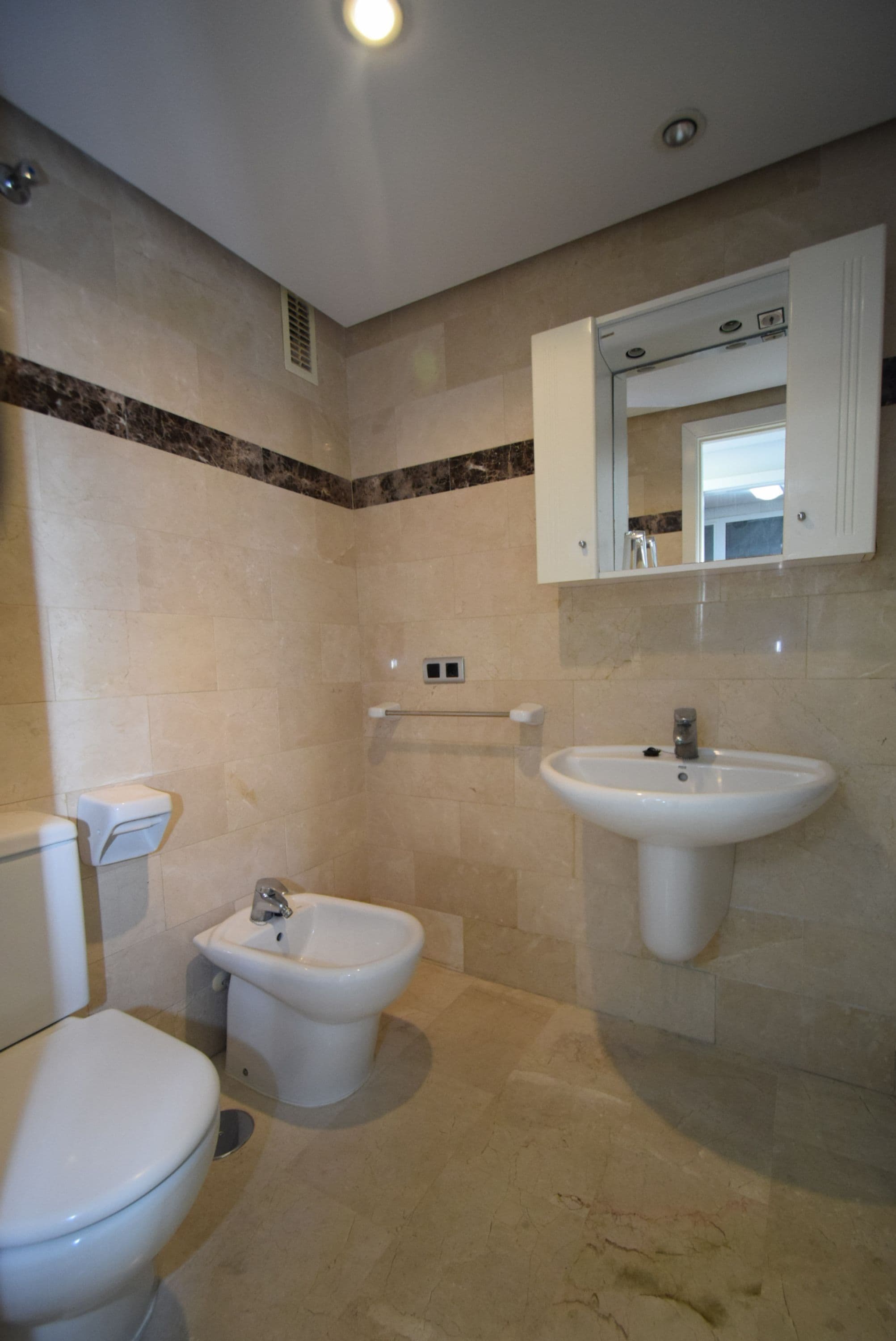 A bathroom with a toilet, bidet, and sink.