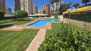 Ein Wohngebiet mit Swimmingpool, gepflegten Rasenflächen und hohen Gebäuden im Hintergrund.