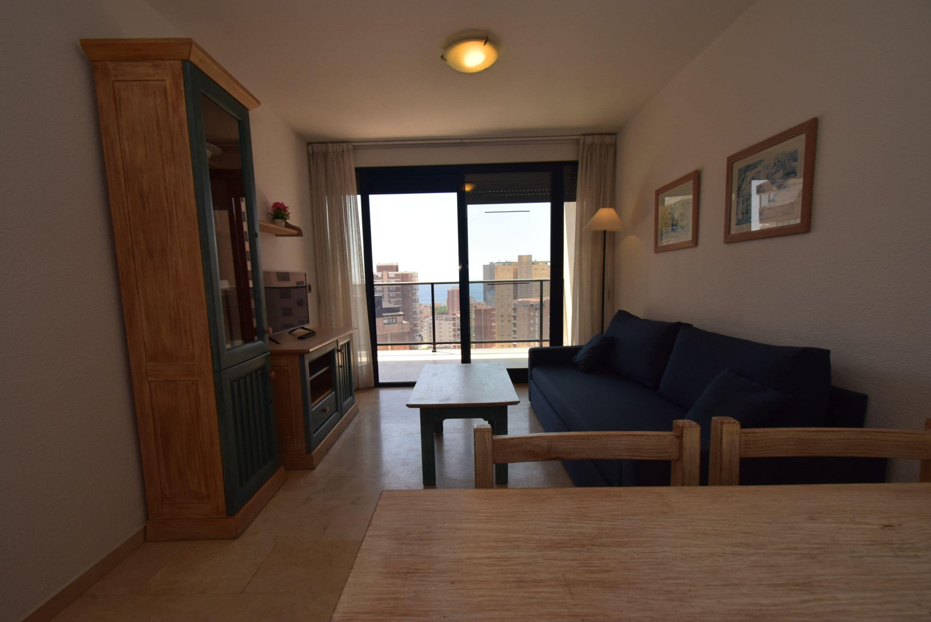 Un soggiorno con divano, tavolo e vista sulla città attraverso ampie finestre.