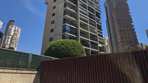 Ein hohes, modernes Hochhaus mit mehreren Balkonen und blauem Himmel.