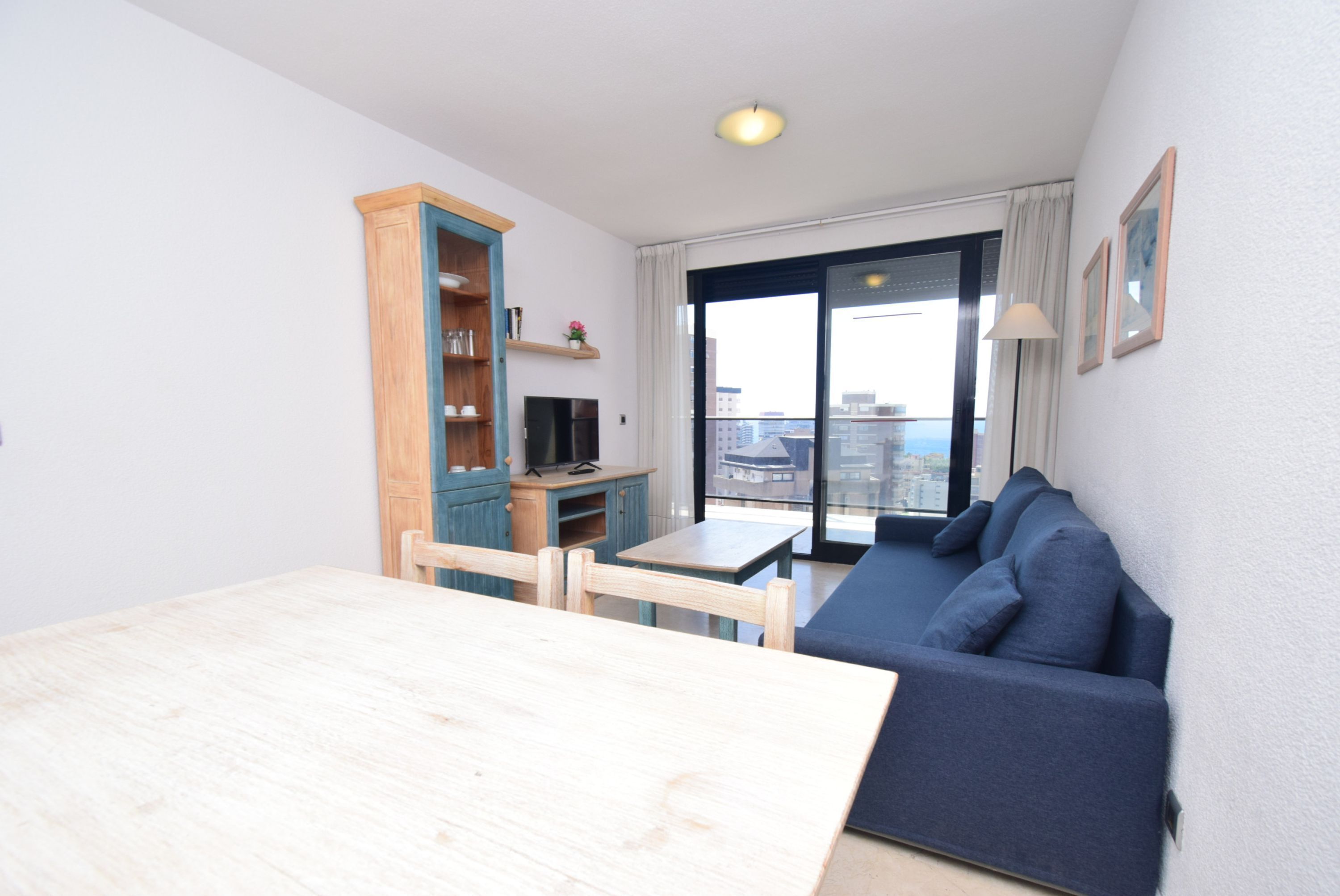 Un espacio de estar con un sofá, una mesa de comedor y un televisor.