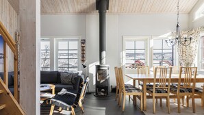 A modern interior with a fireplace, wooden furniture, and large windows offering a view. - Blåstöten - Ramundberget (Bruksvallarna)