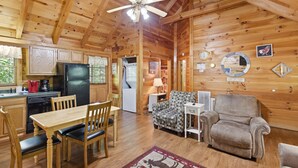 A wooden cabin interior with a dining area, kitchen, and seating. - Bean Pot | Relaxing Cabin Near Dollywood (Pigeon Forge)