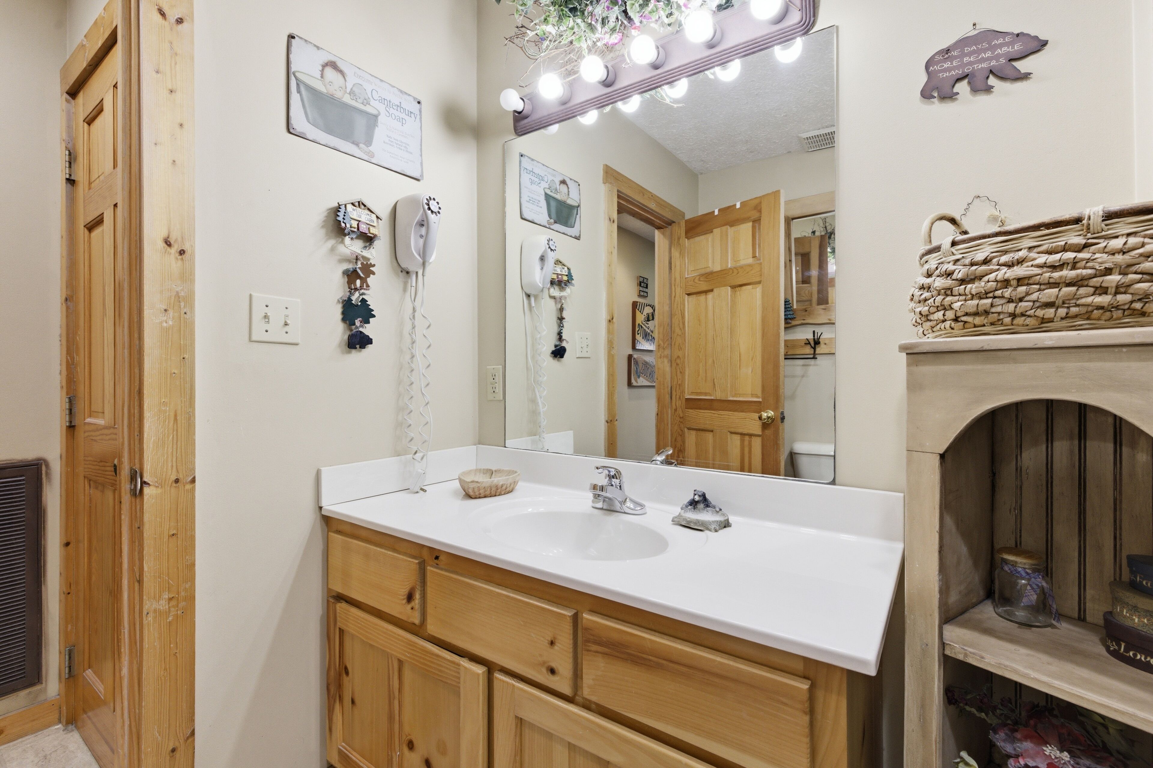 A bathroom with a wooden vanity, a large mirror, and a vanity light.